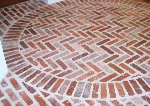 Thin brick floor laid in a herringbone pattern with a circular border