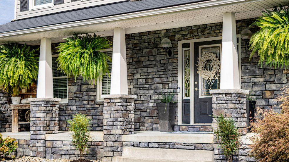 Front porch with gray ProVia manufactured stone walls and stone-wrapped column bases