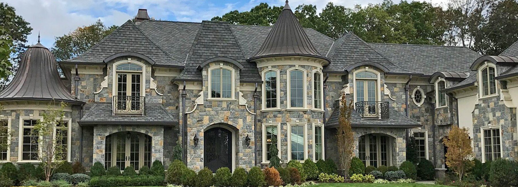 French-style estate home clad in R Stone natural thinstone with turrets and arched windows