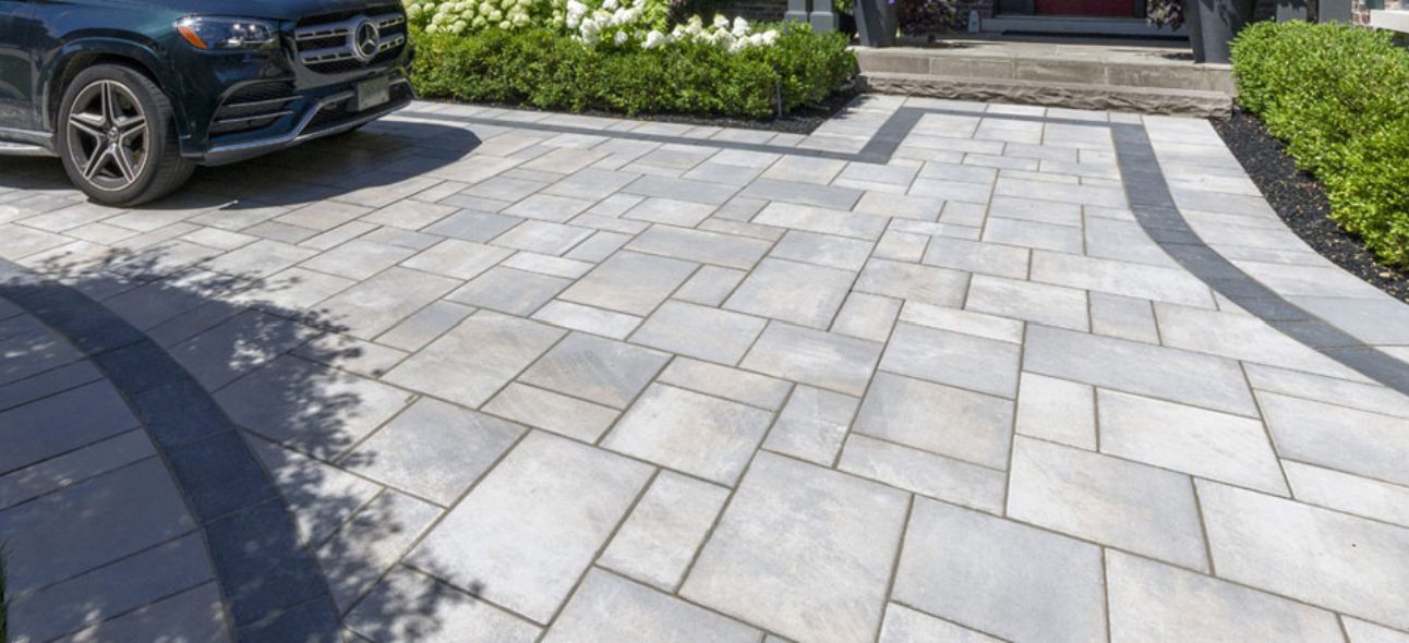 Unilock paver driveway with contrasting border beside a garden bed