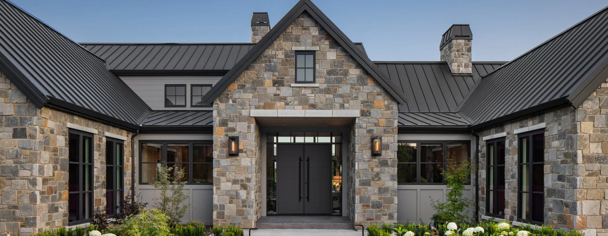 Modern farmhouse exterior clad in Pangaea natural stone with metal roof