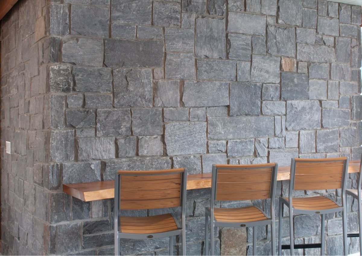 Pangaea natural stone feature wall with a live-edge bar counter and stools