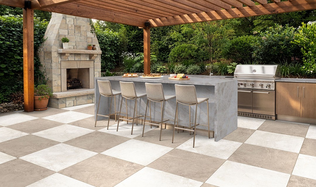 Large-format MSI porcelain tile patio under a cedar pergola with stone fireplace and outdoor kitchen island