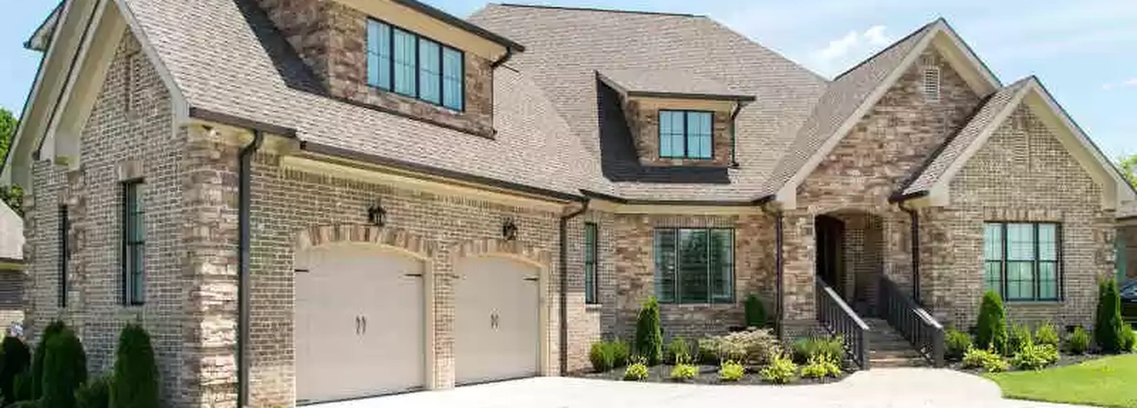 Stone veneer home with arched garage doors