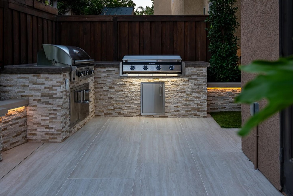 Outdoor kitchen clad in MSI stacked stone veneer with built-in grills and under-counter lighting