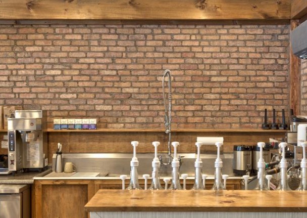 Cafe counter with a full thin brick accent wall behind the bar