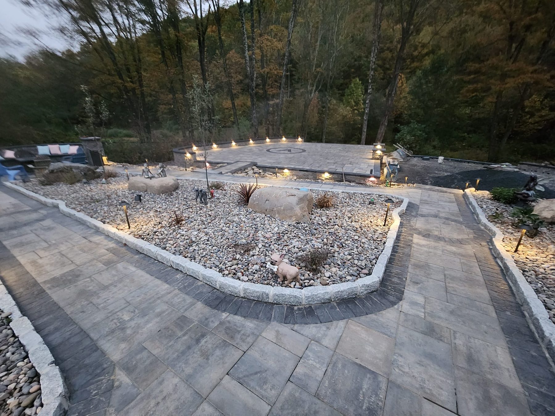 Paver patio at dusk with seating area and landscaped stone border