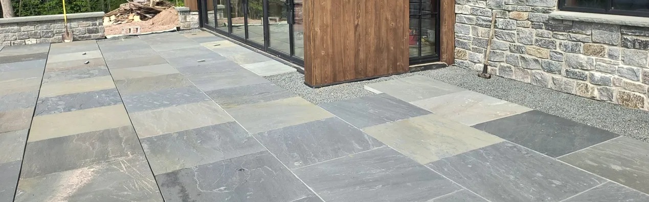 Bluestone pattern patio outside a stone home