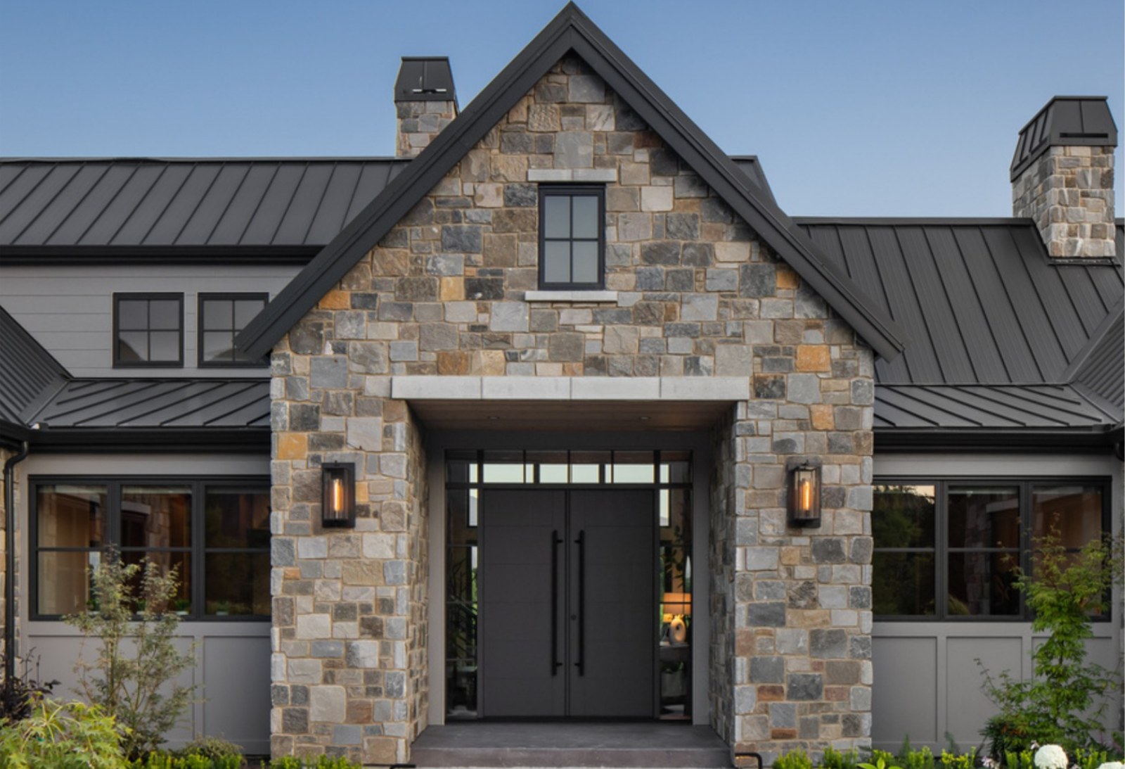 Modern farmhouse entry clad in Pangaea natural stone veneer with black double doors