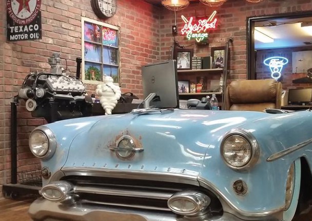 Garage-themed office with thin brick walls and a vintage car-front desk
