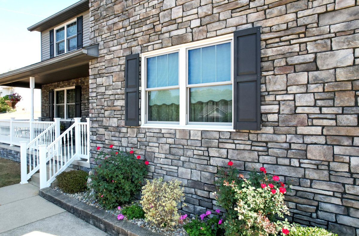 ProVia stone veneer exterior wall framing a window with dark shutters