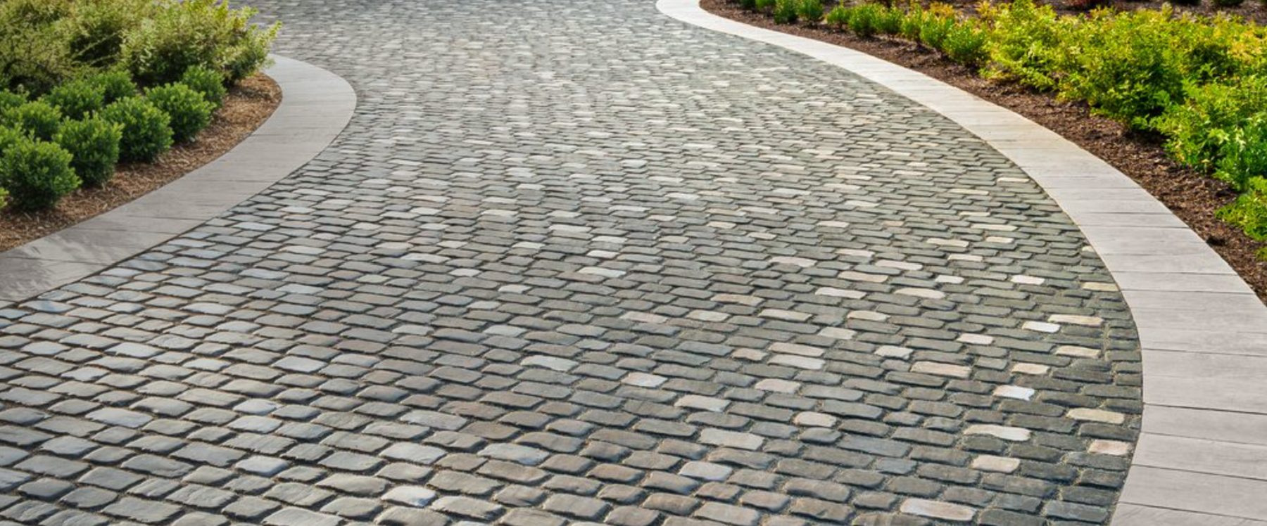 Curved cobblestone-style Unilock driveway with paver border