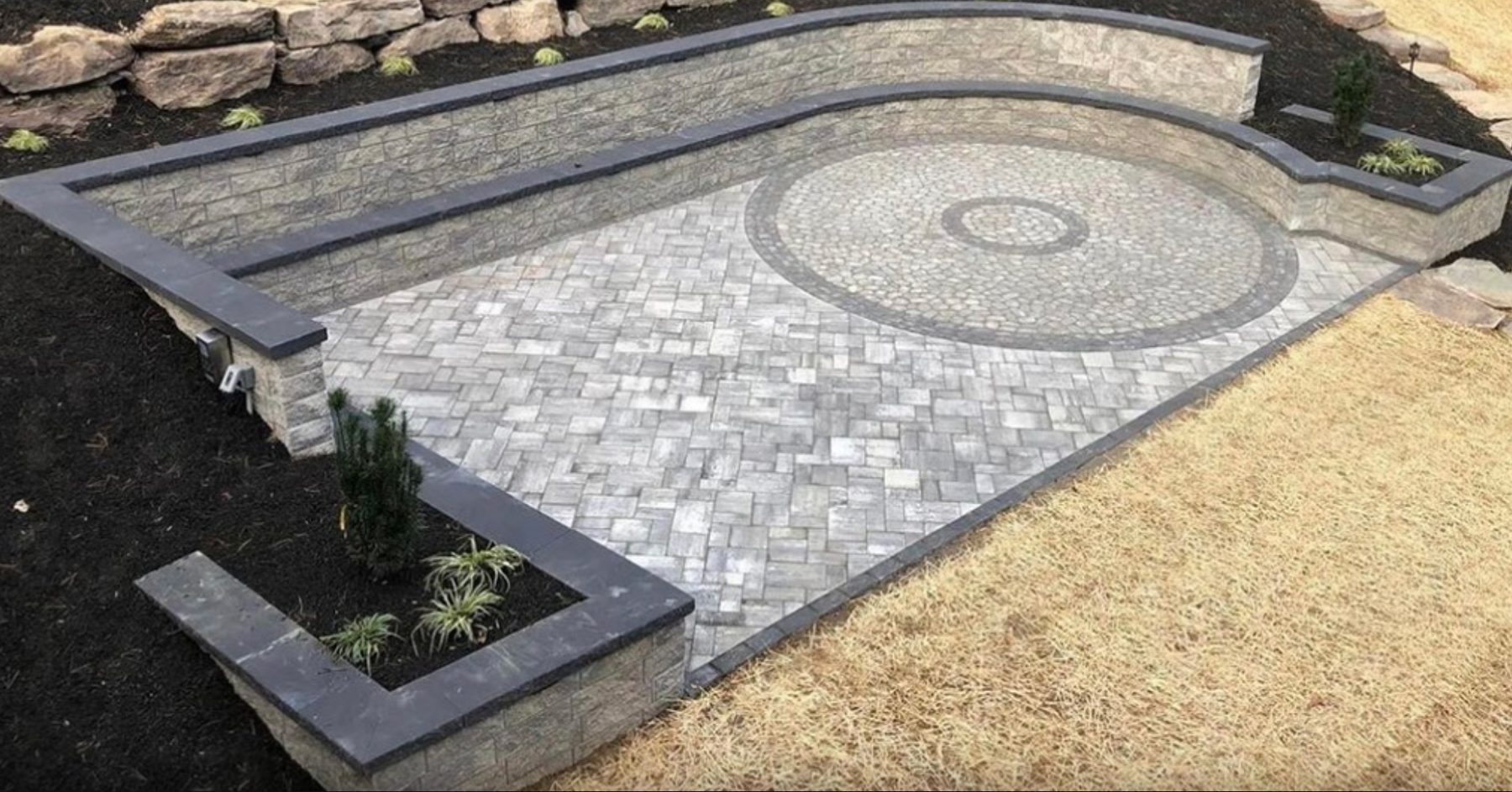 Cambridge paver patio with circular medallion inlay framed by retaining walls