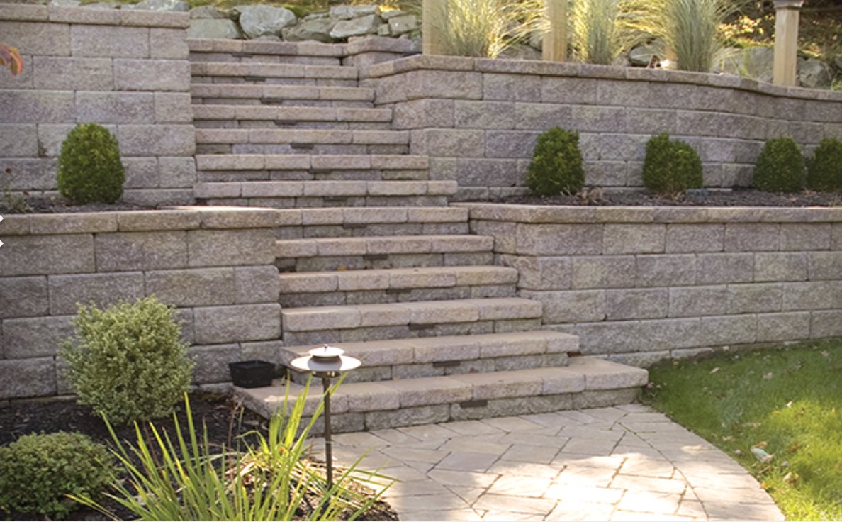 Two-tier Keystone retaining walls with built-in block steps leading down to a paver walkway